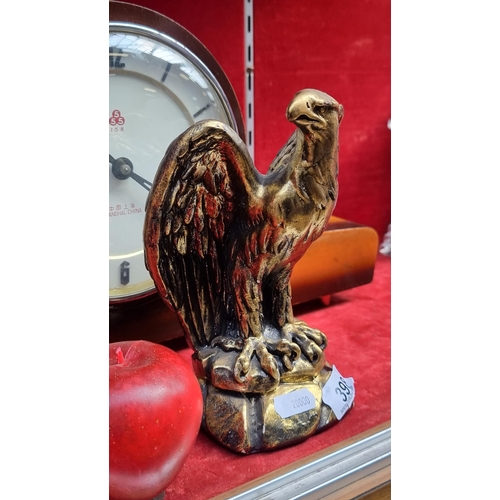 398 - An ornate gold toned figure in the form of an eagle perched on a stone.