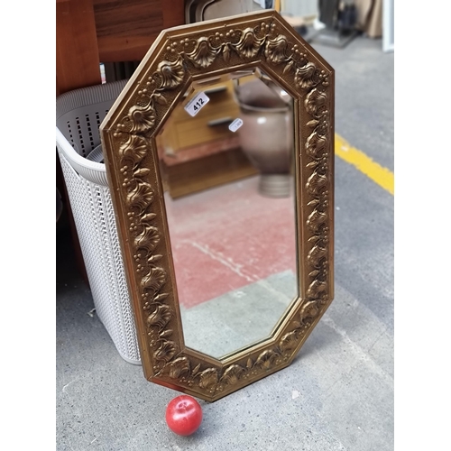 412 - An elegant vintage wall mirror in a hexagonal form with bevelled glass housed in an ornate embossed ... 