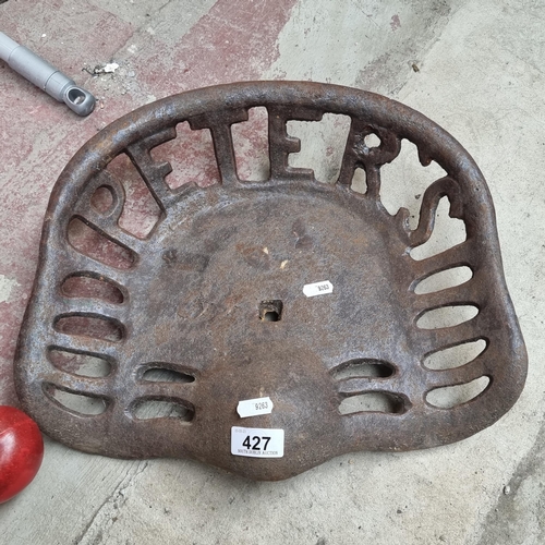 427 - A cast metal tractor seat with a pierced design reading 'Peter's'.