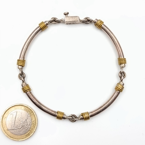 11 - A continental silver link and space bracelet, which features gilt metal twist accents and a safety c... 
