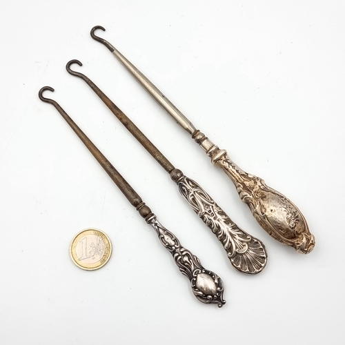 57 - A group of three antique sterling silver handled Repousse design boot hooks. Lengths:1 18cm and two ... 