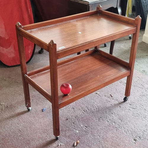 900 - A vintage wooden drinks trolley with gallery back and a lower tier for further storage. All held on ... 