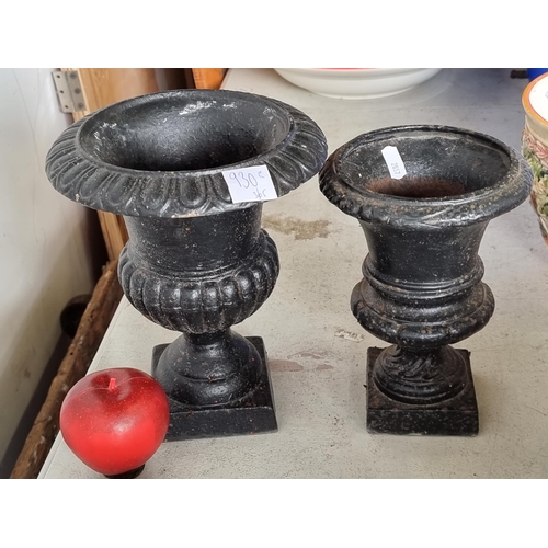 930 - Two heavy neat size  cast iron planters in the form of neoclassical urns with a black finish.