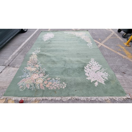 947 - Star Lot : A very  large low pile rug in a mint green with floral border. Mm: 380 x 271 cm