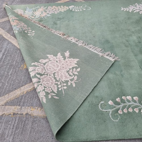 947 - Star Lot : A very  large low pile rug in a mint green with floral border. Mm: 380 x 271 cm