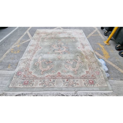 948 - A very large Chinese wool on cotton low pile rug in a mint green with dragon ornament throughout. Mm... 