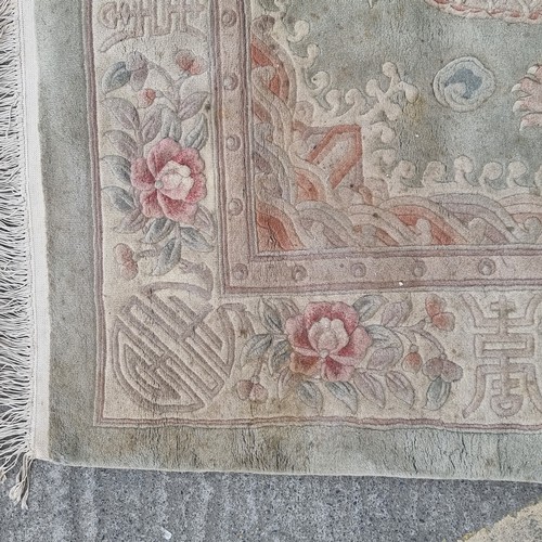 948 - A very large Chinese wool on cotton low pile rug in a mint green with dragon ornament throughout. Mm... 