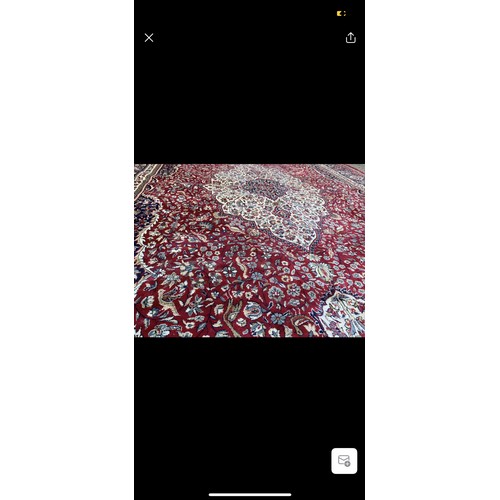 923 - Star lot : A large elegant wool rug with a rich floral design in jewel tones of red and blue accentu... 