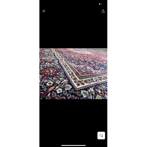 923 - Star lot : A large elegant wool rug with a rich floral design in jewel tones of red and blue accentu... 