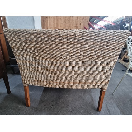 449 - A charming rattan two-seater sofa with curved armrests and wooden legs.