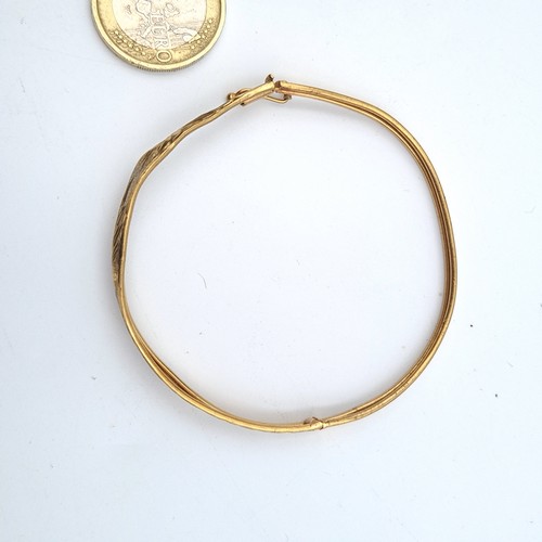 19 - A stunning and intricately formed antique 9 carat gold bangle, featuring an attractive hammered foli... 