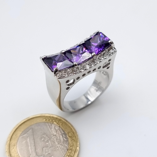 630 - A three stone Amethyst sterling silver cocktail ring, set with an unusual curved gem stone mount. Ma... 