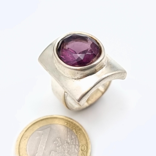 634 - A striking heavy gauge,  sterling silver ring, set with a bright natural facet cut Amethyst. Ring si... 