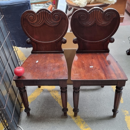 659 - A matching pair of Victorian carved mahogany hall chairs.  Featuring spiral carved motifs to backres... 