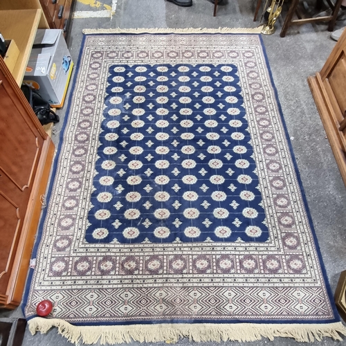 665 - Star Lot : A large Persian style floor rug in shades of blue and cream with red detailing and a long... 