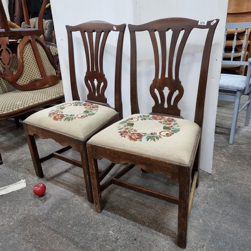 676 - A pair of antique oak dining chairs boasting a pierced splatback and padded seats upholstered in an ... 