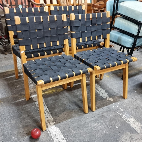 686 - A set of four stylish dining chairs with woven black strap seats and backrests set on well made teak... 