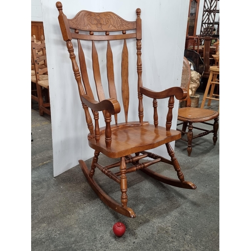 721 - A very large and well made rocking chair with a tall slatback backrest featuring a floral carved mot... 