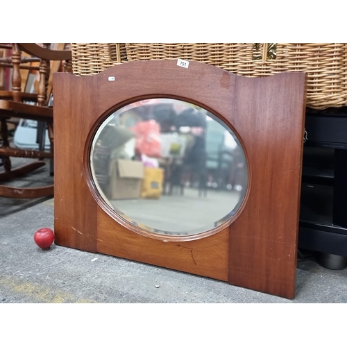 751 - A large wall mirror with thick wooden frame with serpentine edge top inset with bevelled oval mirror... 