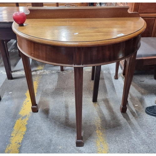 787 - A beautiful demilune hall table. A lovely and timeless example, with a gallery back and tapered legs... 