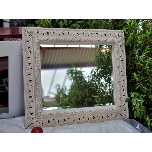 797 - A very elegant large beveled mirror housed in an elaborately carved wooden frame, with a painted whi... 