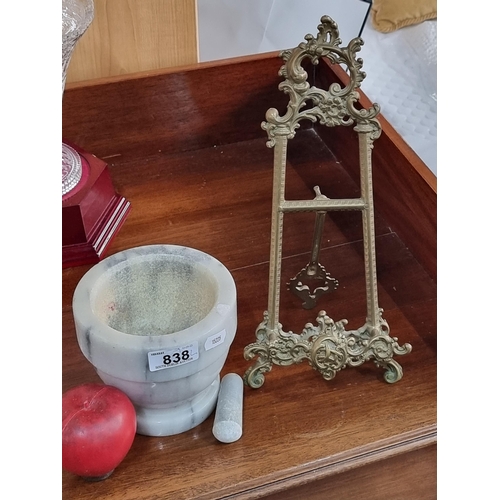 838 - Two items including a solid marble mortar and pestle and a brass book holder with foliate frame.