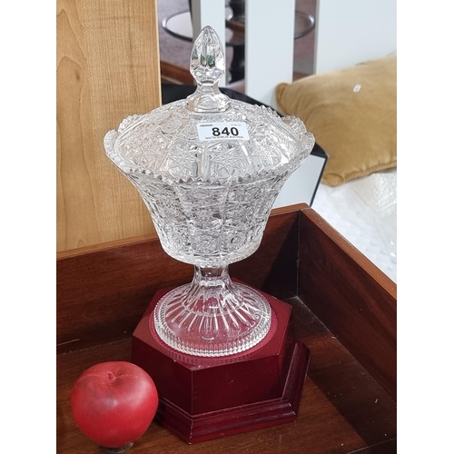 840 - A lovely cut crystal bon bon dish with scalloped edge and lid with finial. Held on a wooden plinth b... 