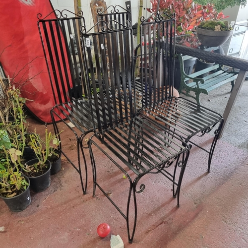 853 - Four heavy black wrought iron slat back garden chairs with scroll detail to top. In a black finish. ... 