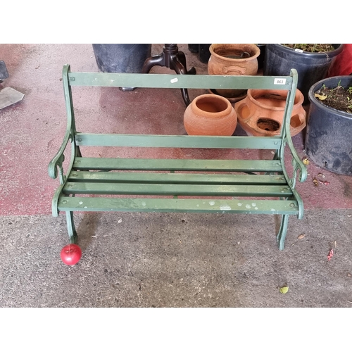 863 - A delightful vintage child's garden bench with wooden slat back, cast metal scroll ends and a green ... 