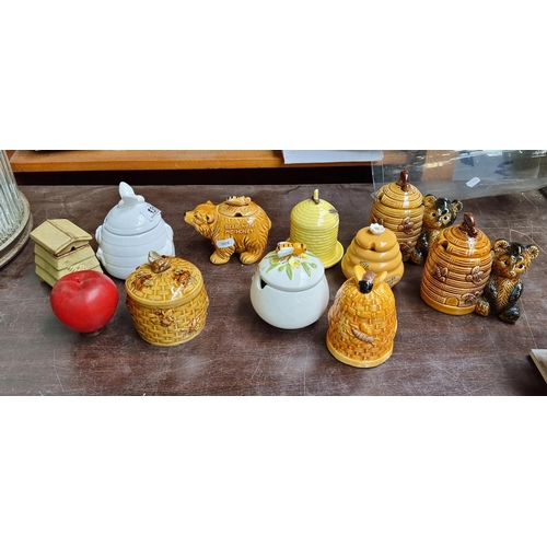 931 - Ten precious ceramic honey pots including examples in the form of hives with bear and bee decoration... 