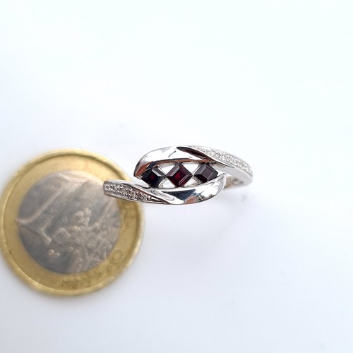 651 - Star Lot : A beautiful 9 carat White Gold three stone Garnet ring, set with White Sapphire shoulders... 