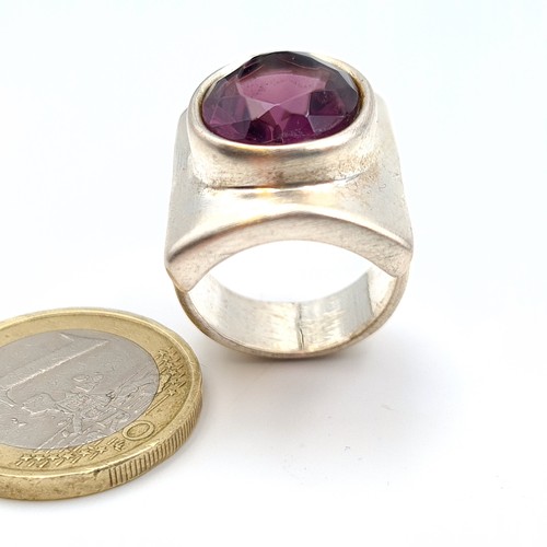 634 - A striking heavy gauge,  sterling silver ring, set with a bright natural facet cut Amethyst. Ring si... 