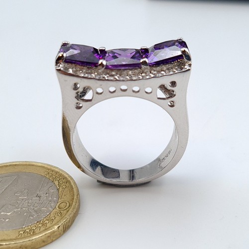 630 - A three stone Amethyst sterling silver cocktail ring, set with an unusual curved gem stone mount. Ma... 