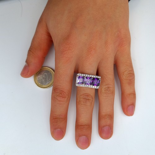 630 - A three stone Amethyst sterling silver cocktail ring, set with an unusual curved gem stone mount. Ma... 