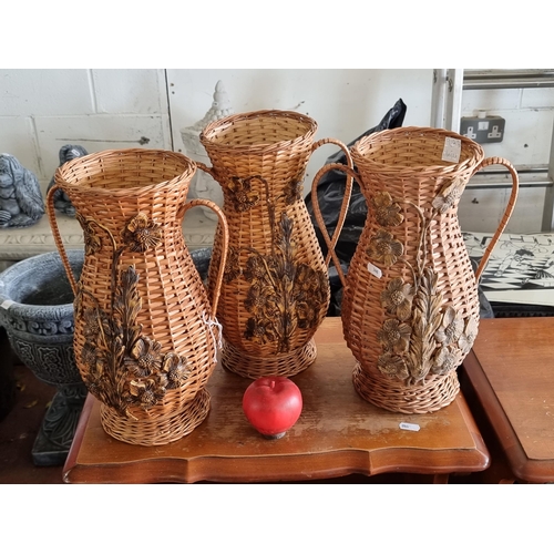 928 - A set of three charming wicker dry flower vases boasting large handles and relief floral appliques t... 