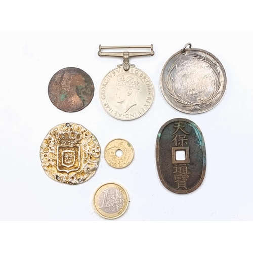 An eclectic collection of coins, medallions and medals. Consisting of a World War II 1939 - 45 medal, a Japanese Edo period bronze ancient coin, a Belfast proficiency medallion, a Victorian penny, a Spanish example and a possible Armada embossed coin.