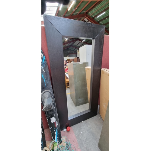 426 - A very large contemporary full length mirror. Housed in a heavy wooden frame with wood grain and dar... 