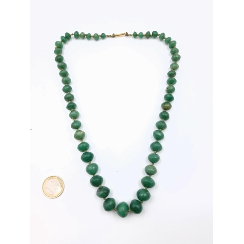 596 - Star Lot : An heavy gauge antique Jade graduated stone necklace, set with a gold clasp. Necklace wel... 