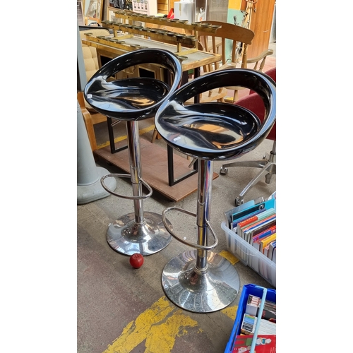 657 - A pair of chic bar stools with tubular chrome bases and glossy black seats. Height adjustable.