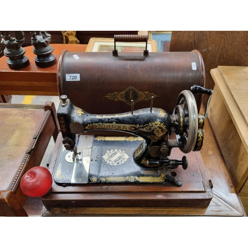 720 - An antique manual Singer Sewing machine with original branded wooden travel case. Machine has beauti... 