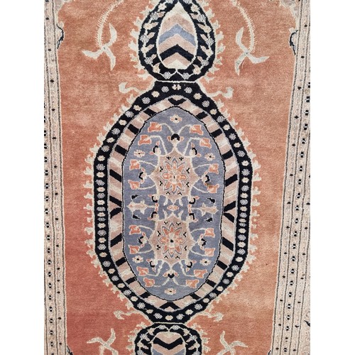 776 - Star Lot : A large hand made woolen rug in shades of terracotta, sky blue and sand. Made by Fazal El... 