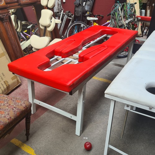 422 - A heavy duty folding massage table. Designed on a steel frame with red leather padded upholstery. A ... 