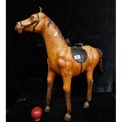 235 - A large horse figure with wooden form and leather exterior. Adorned by glass eyes, a braided bridle ... 