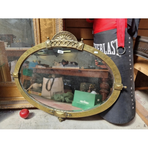 293 - A gorgeous antique beveled ovular wall mirror set in a hammered brass frame boasting Neoclassical mo... 