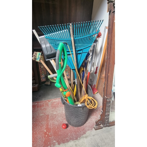 307 - A large collection of gardening tools including rakes, shovels, saw, Powerbase strimmer and plenty m... 