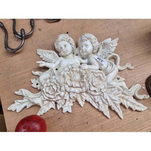 338 - A heavy cast metal wall ornament depicting a pair of cherubs in high relief.