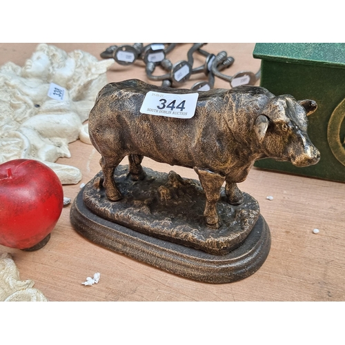 344 - A heavy quality cast metal figure of a bull held on an oval base. In a brushed brass effect finish.