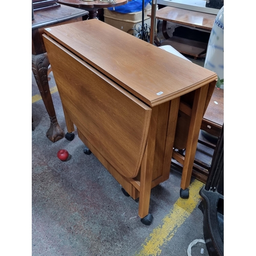 452 - A fantastic gate leg mid century drop leaf table with two legs that fold out to each side, flanking ... 