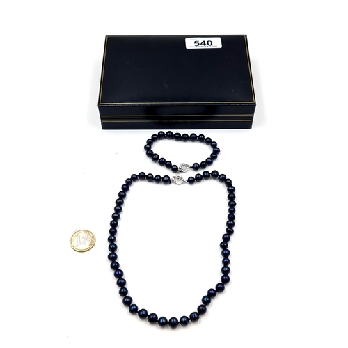 540 - A matching set of black cultured pearl necklace and bracelet. Each set with a sterling silver rose c... 