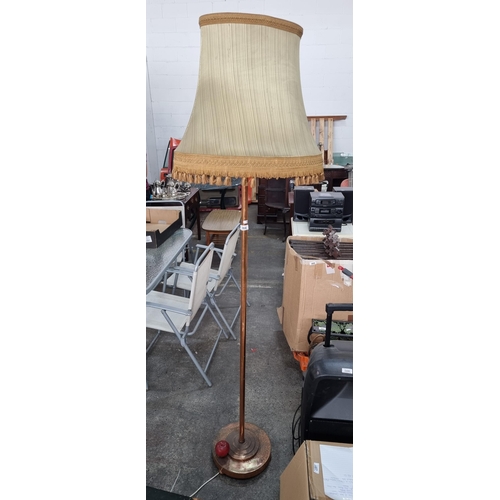 568 - A tall and heavy floor standing lamp with a brass and copper base and topped in a large tassled shad... 